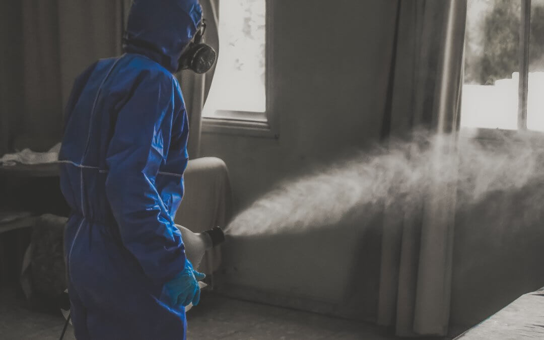 Technician in PPE fogging and sanitising a room to disinfect air and surfaces