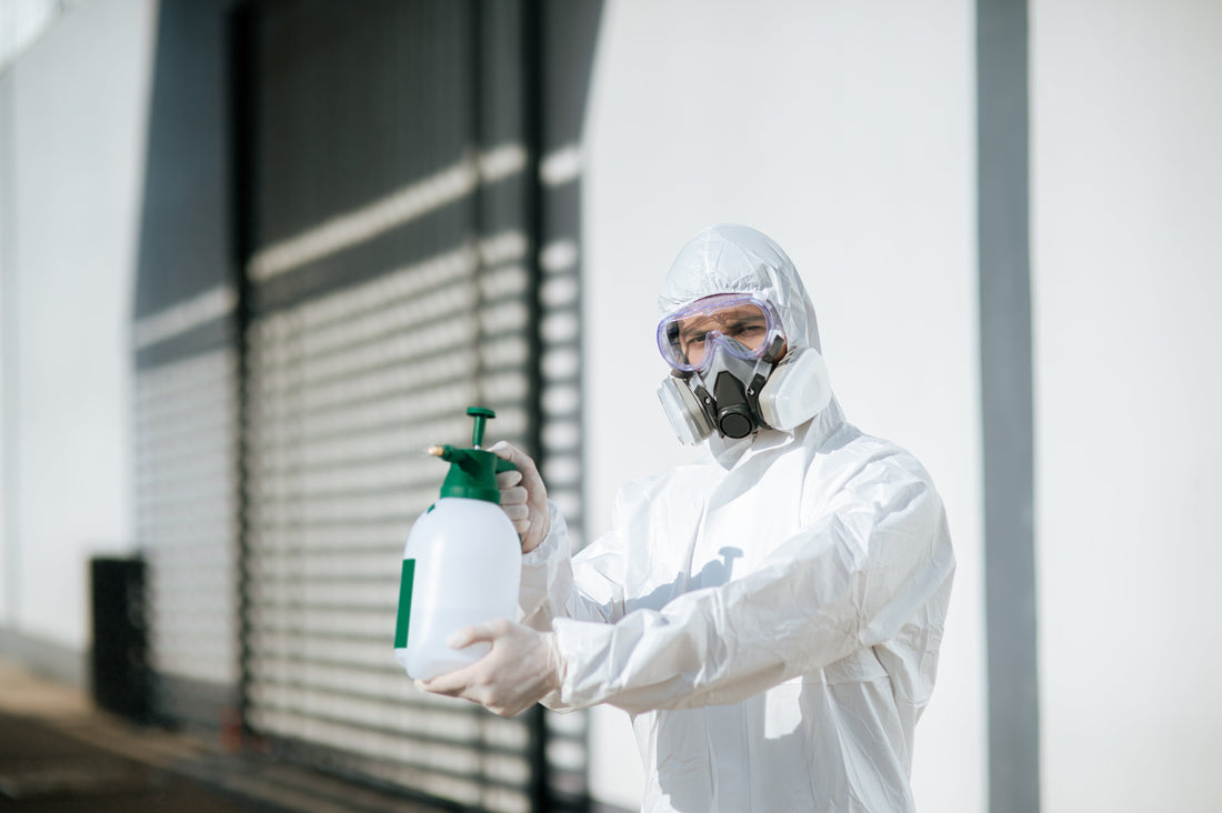 Technician in protective suit using spray equipment for odour removal and disinfection